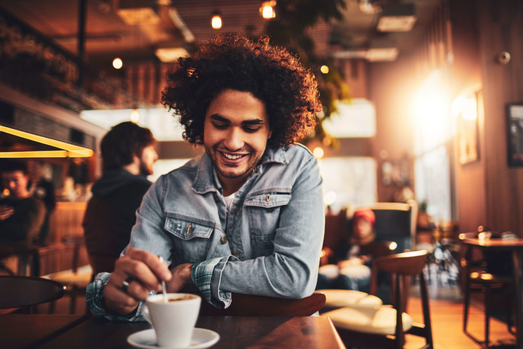 Image of Arab man sitting in a coffee shop smiling