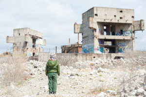 Child standing in front of ruins