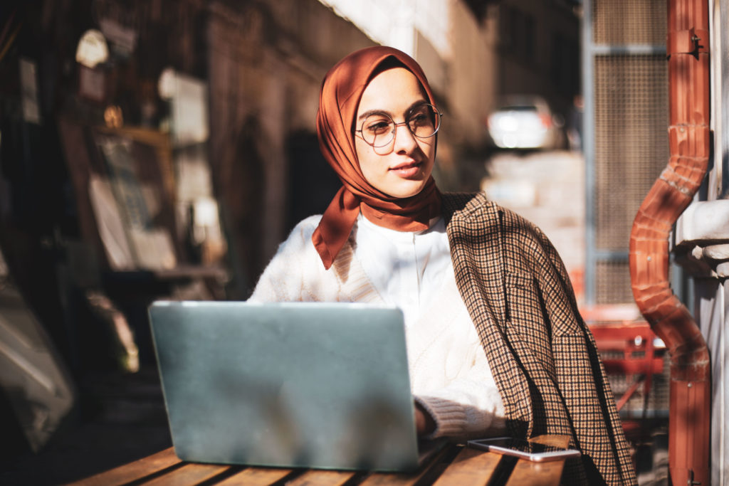 Image of young woman sitting at table in front of computer